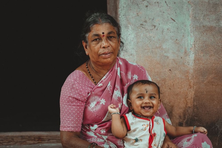 A grandmother in a sari holding a smiling baby on her lap