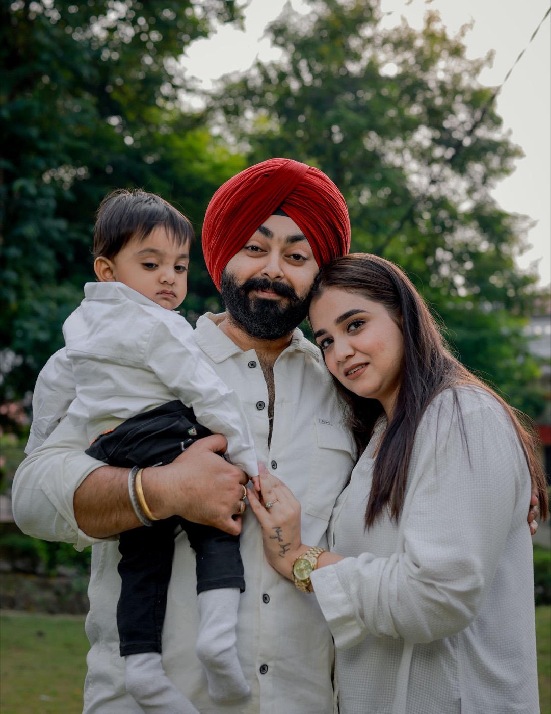 A father, mother and young child embracing in a park