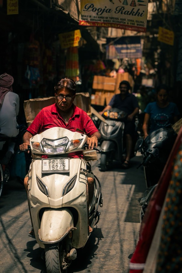 A man in a helmet riding a scooter through city traffic